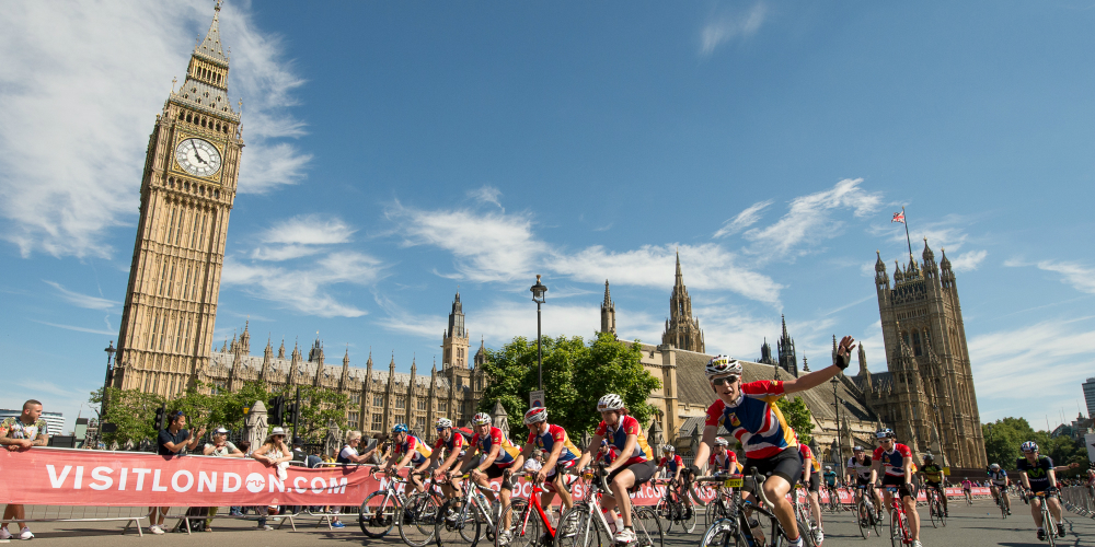 A group of cyclists ride past Big Ben in London - the roads are closed and banners line the streets at a cycling event.