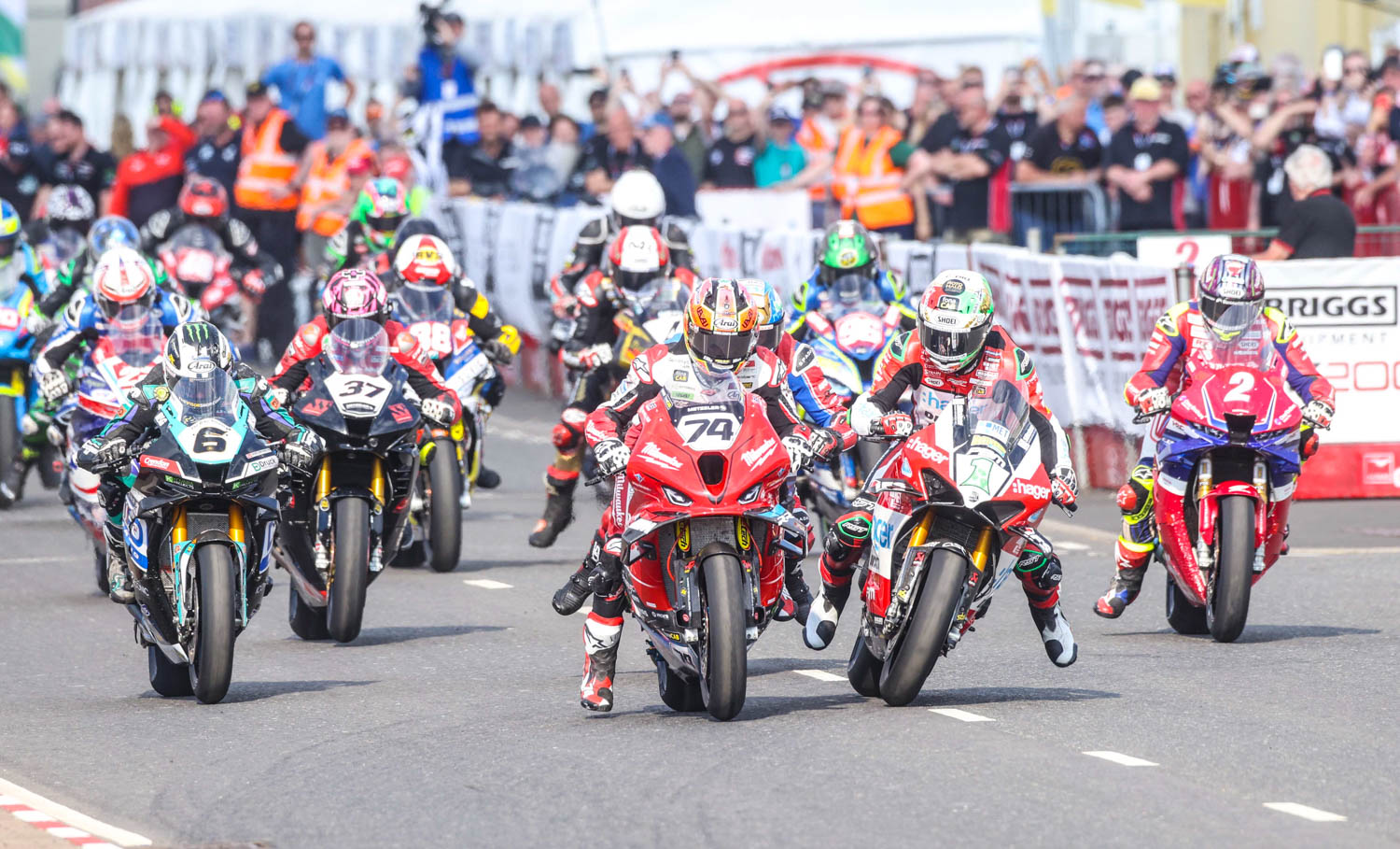 A group of people on motorbikes, set off from the start line.