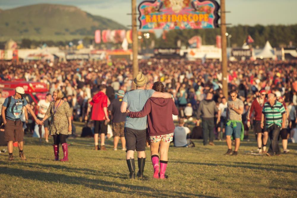 A large crowd on people looking at a stage at a music festival
