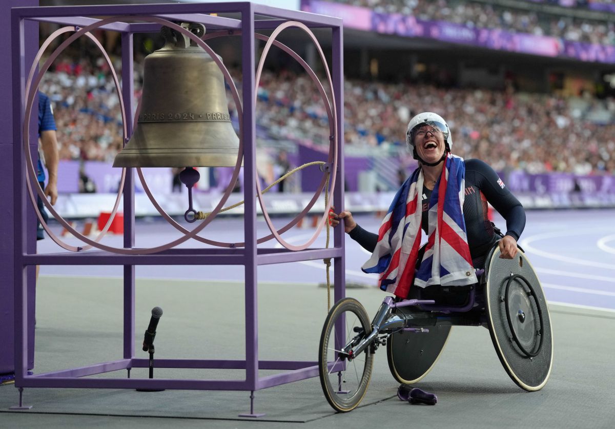 Hannah Cockcroft is in her racing wheelchair, ringing the bell in the stade de france as a gold medal winner, the union jack flag around her neck.