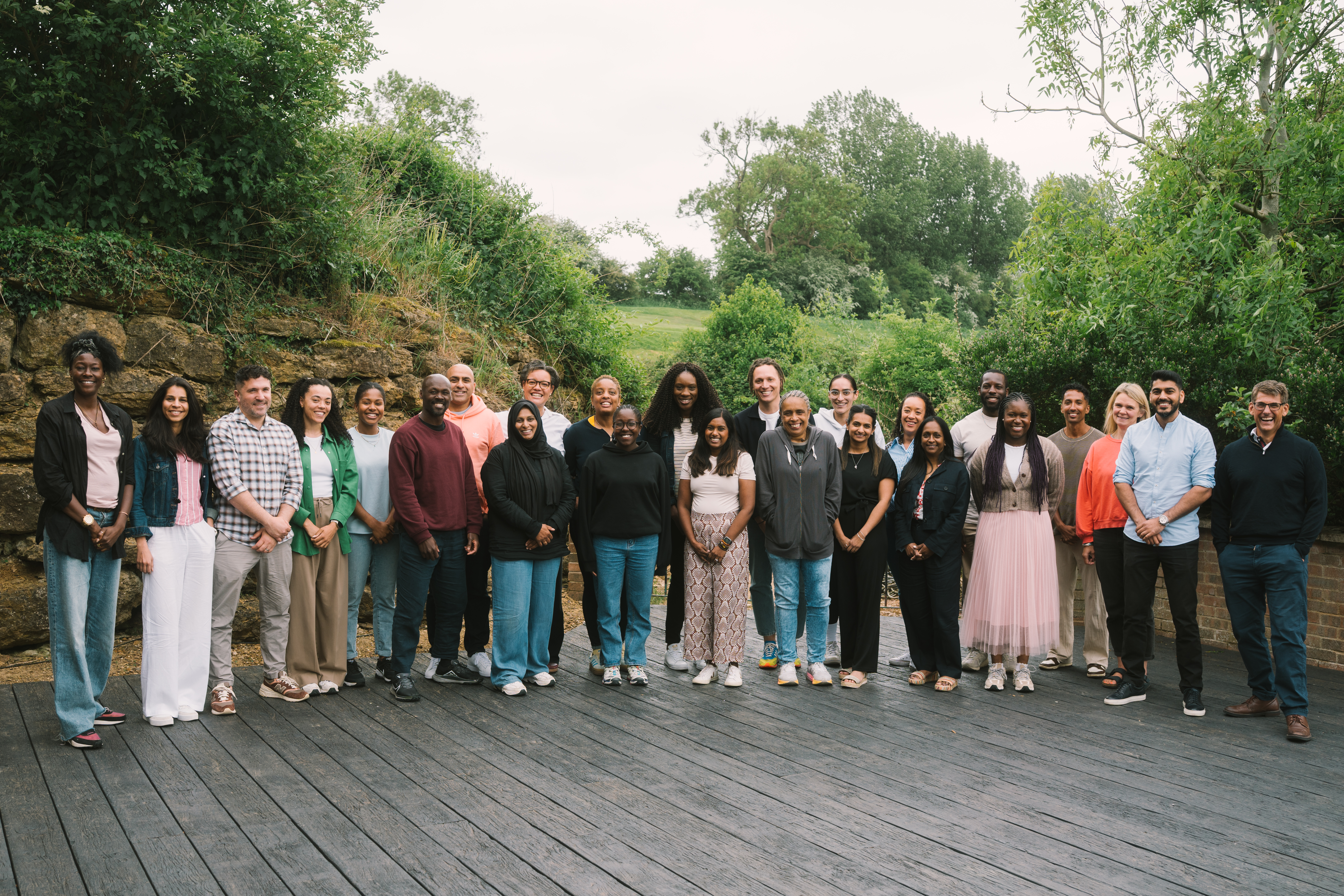 Group of people on a wooden deck overlooking trees.